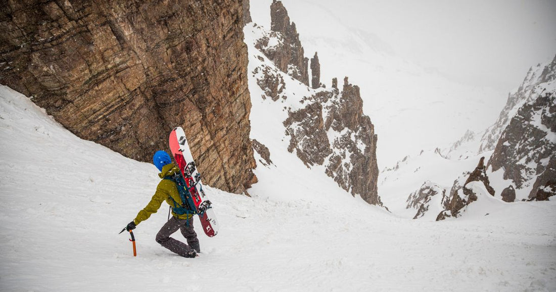 Splitboard mountaineer with a Weston Ridgeline Splitboard on his back and holding an ice axe while climbing a snowy steep mountain couloir