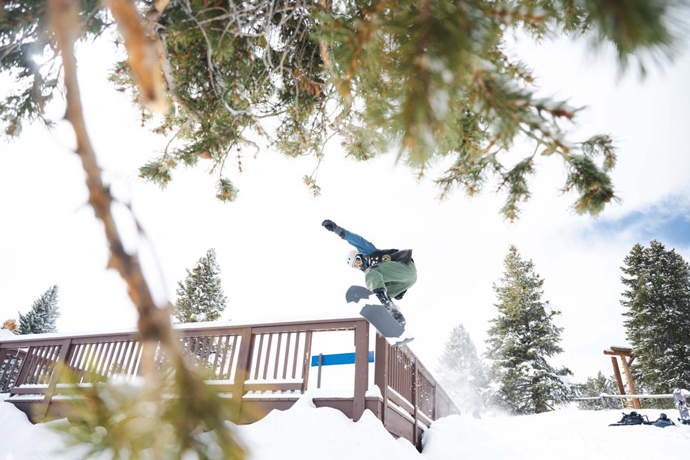 Snowboarder jumping off of a porch on a ski resort on a snowy day