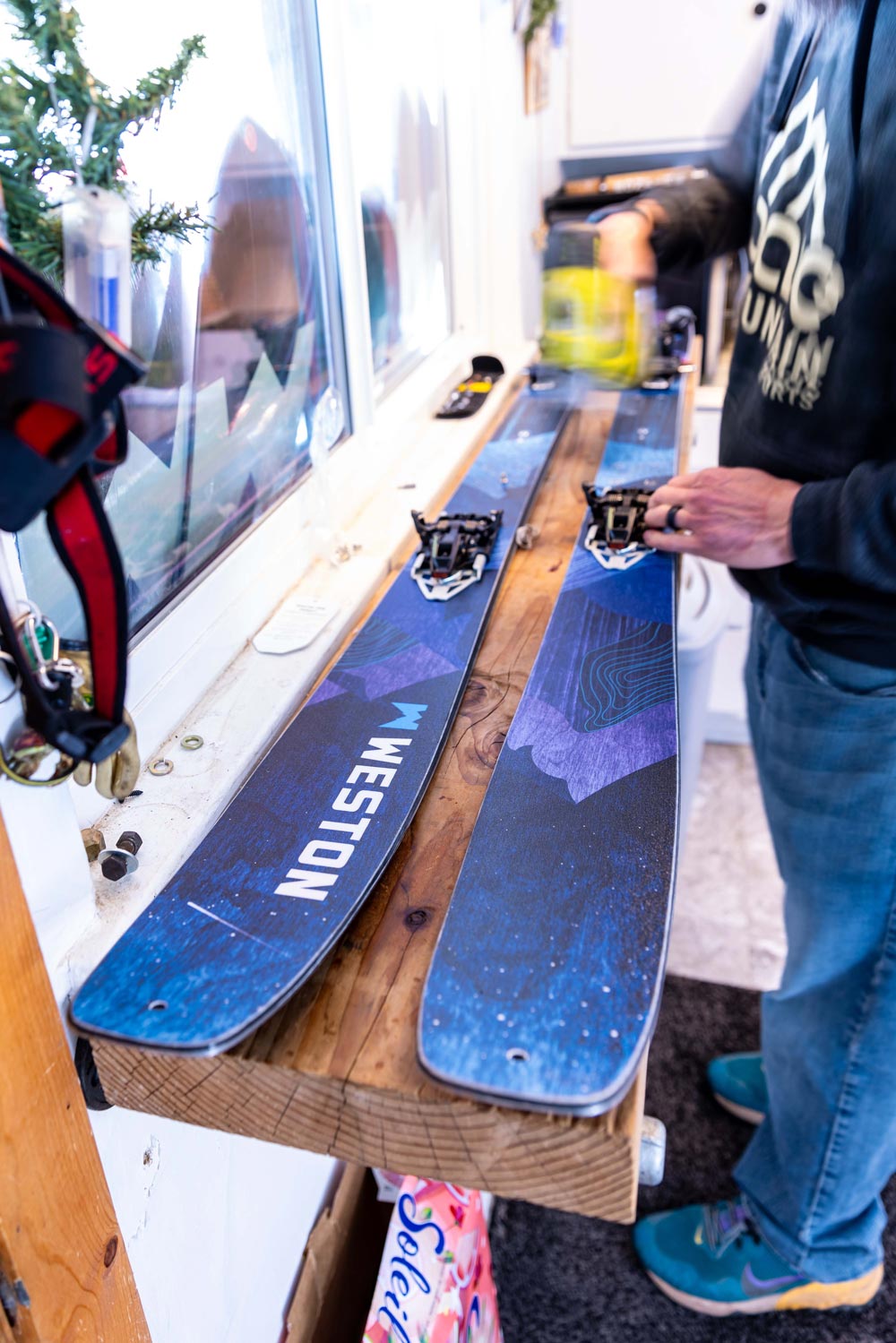 person mounting ski tech bindings on a pair of weston skyline skis on top of a wooden table