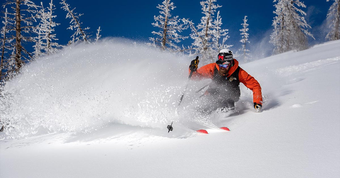 Backcountry skier skiing on the Weston Grizzly skis making a deep powder turn on the side of a snowy mountain with bluebird skies and frosty trees in the background
