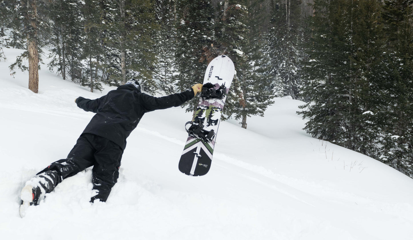 Splitboarder jumping into deep snow with the weston backwoods carbon splitboard in a snowy forest