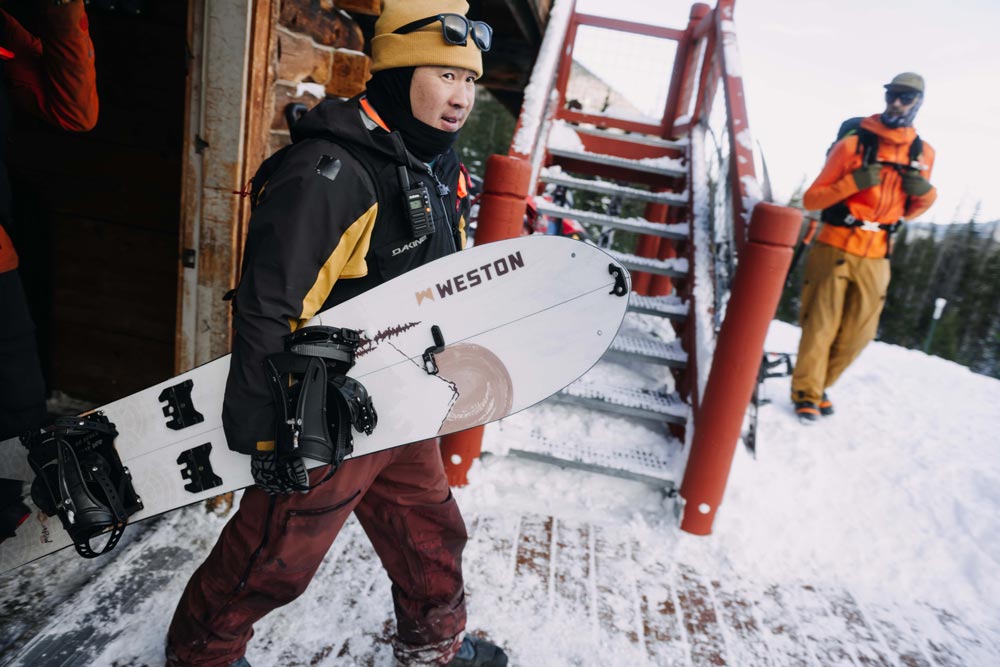 Splitboarder walking out of a backcountry hut holding the weston japow splitboard