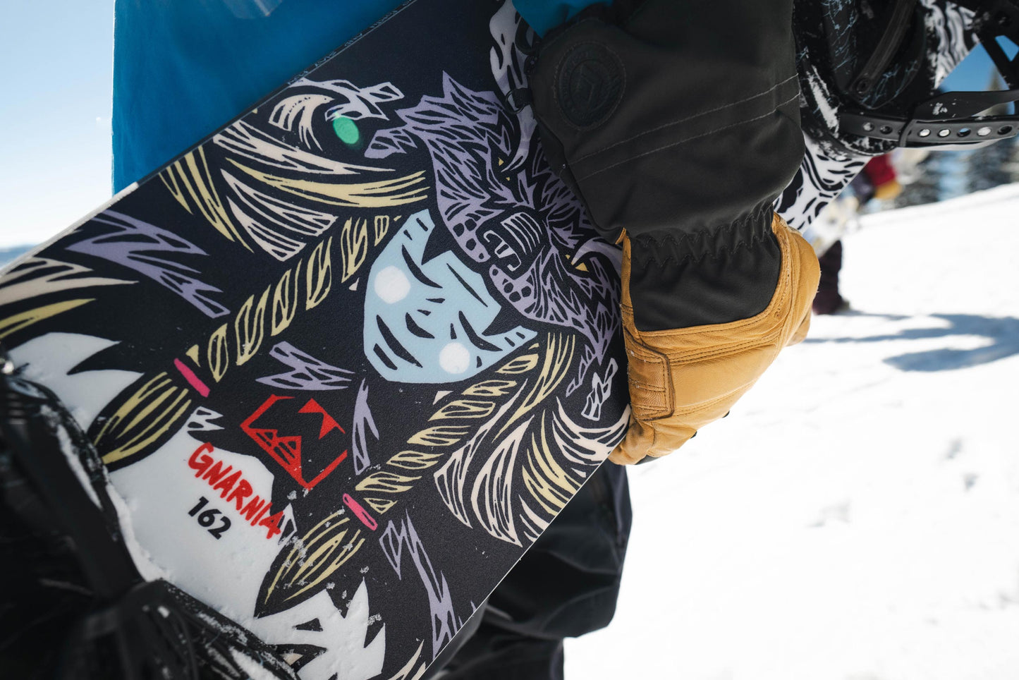Snowboarder holding a weston gnarnia snowboard with a colorful viking woman design in a snowy environment