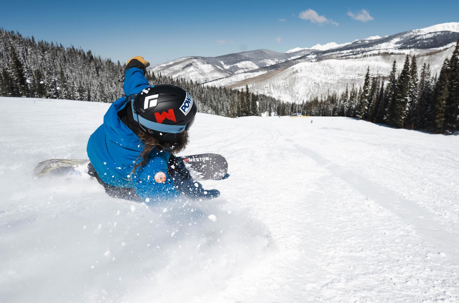 Snowboarder on the weston gnarnia snowboard snowboarding down a snowy slope with mountains in the background