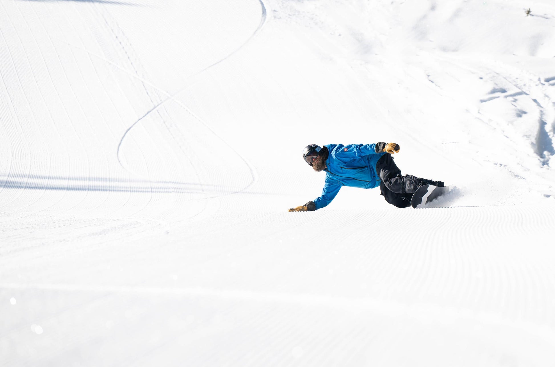 Snowboarder snowboarding on a weston gnarnia snowboard down a snowy slope and touching the ground with his glove