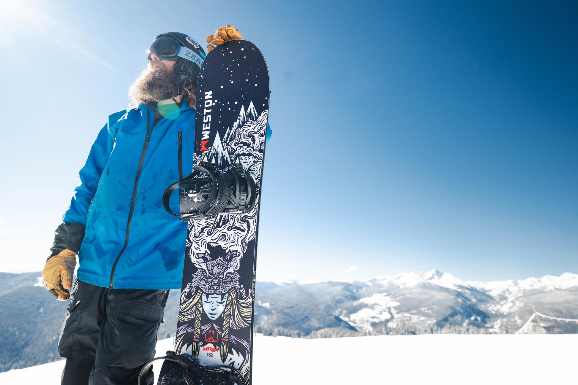Snowboarder holding a Weston Gnarnia snowboard with a mountainous background